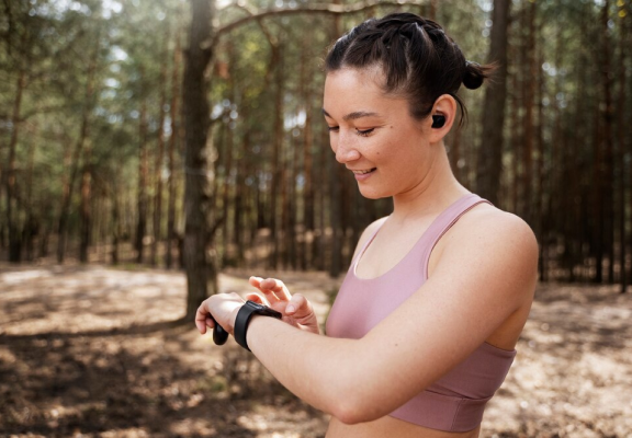 Image de uma mulher interagindo com a tela de um relógio de pulso inteligente.